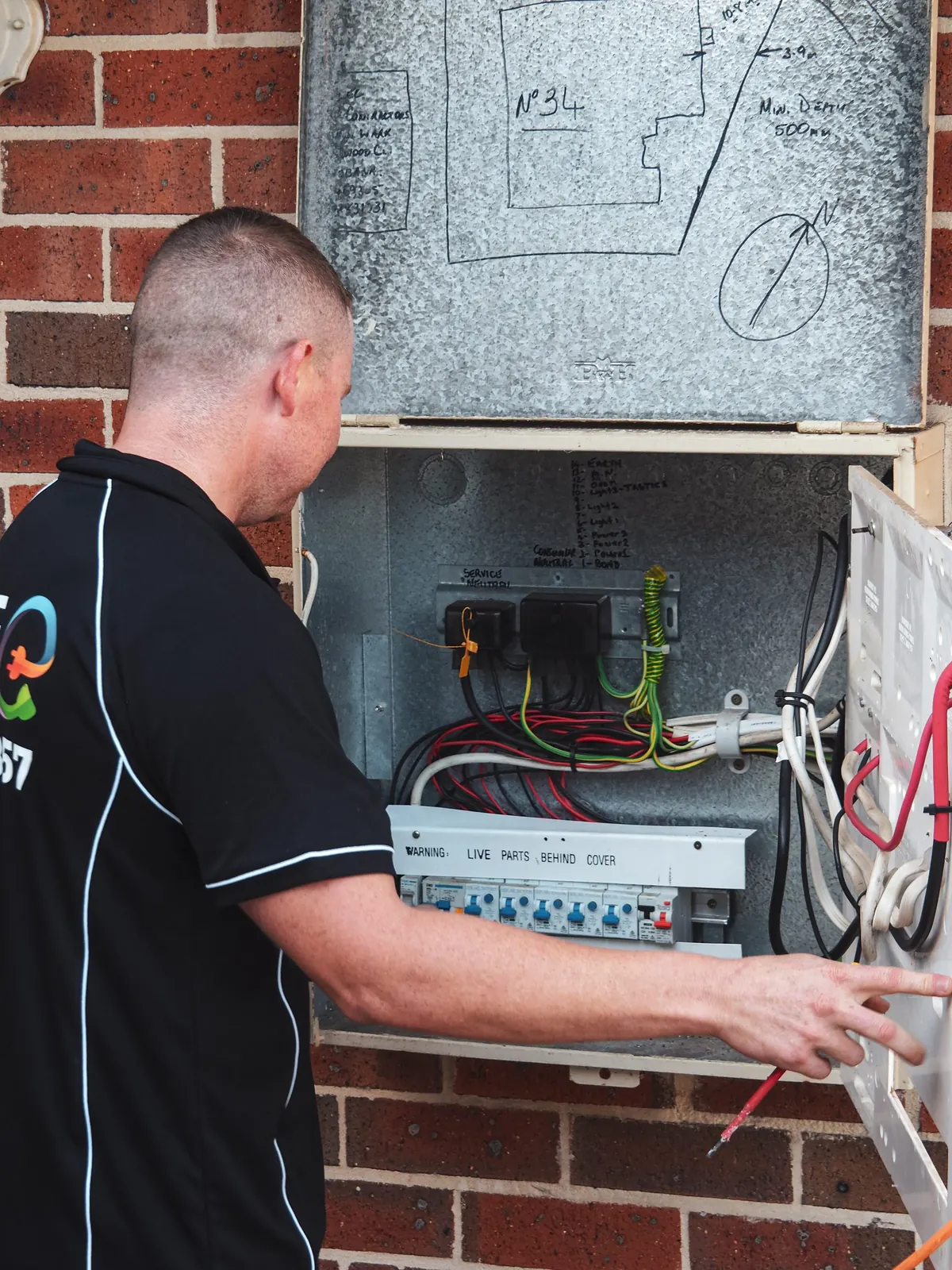 Ben working at an open switchboard on a brick wall