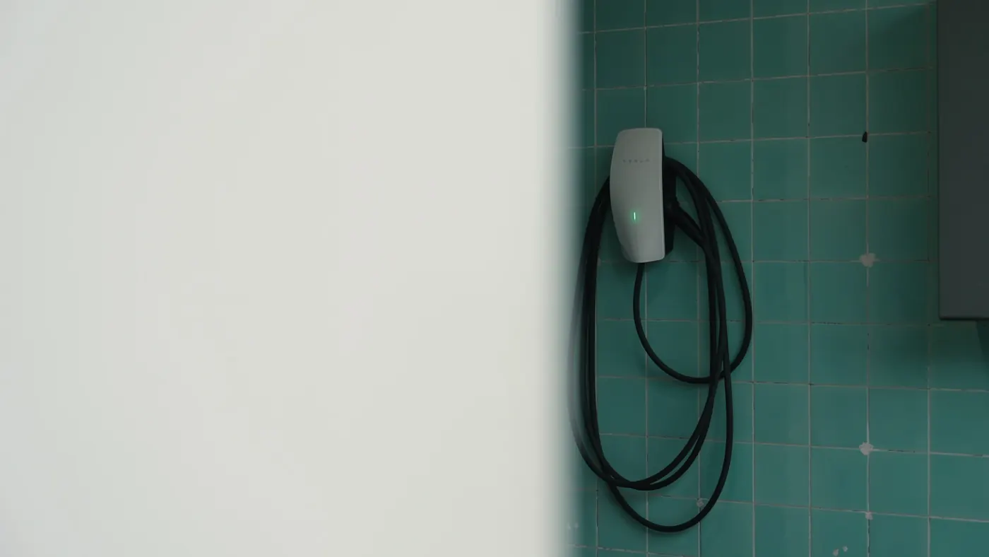 An EV wall charger mounted on teal tiles
